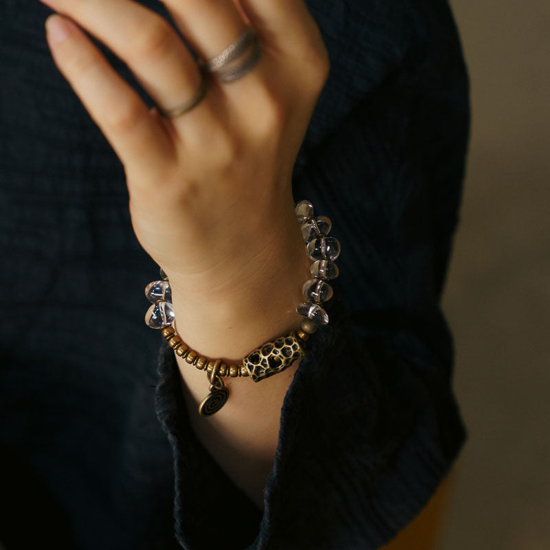 A close-up of a bohemian-style beaded bracelet with vintage metal accents worn on a hand, highlighting the artisanal texture and organic feel.