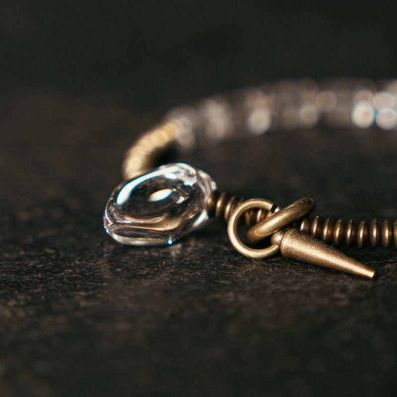 Macro detail shot of the antique brass toggle clasp and decorative spike charm on an artisan bracelet.