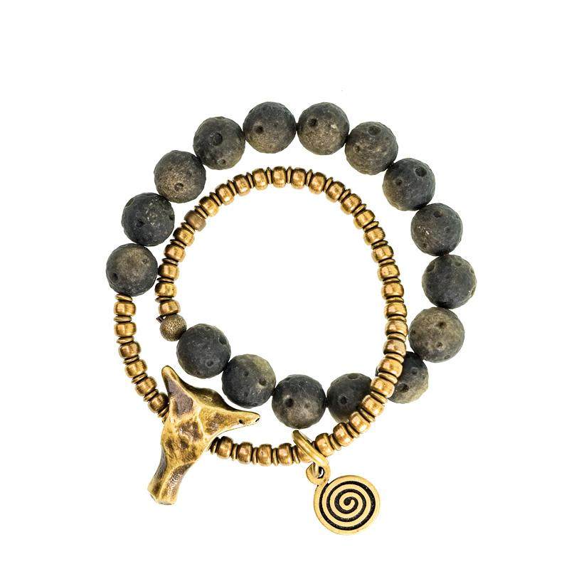 A two-piece stackable bracelet set featuring an antique brass bull head charm, spiral pendant, and porous black lava rock beads on a white background.