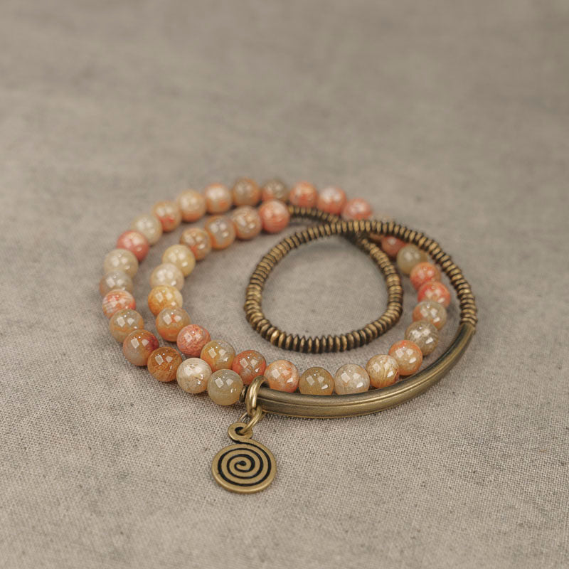 Macro detail of the natural grain in Fossil Coral beads and the antiqued finish of the Serene Lucky spiral charm.
