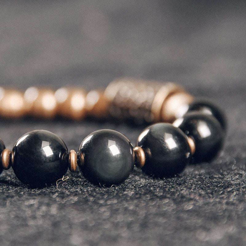 Macro shot of natural polished black obsidian beads, highlighting the smooth surface and grounding energy of the gemstone.