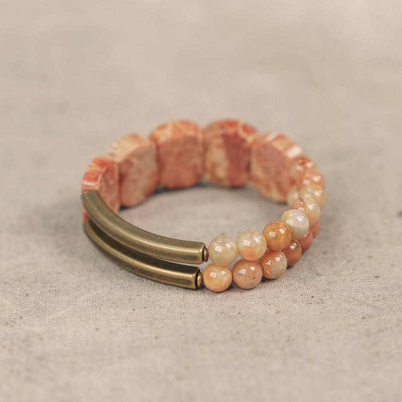 Close-up detail of the natural flower-like chrysanthemum patterns on the Fossil Coral slabs of a Serene Lucky handmade bracelet.