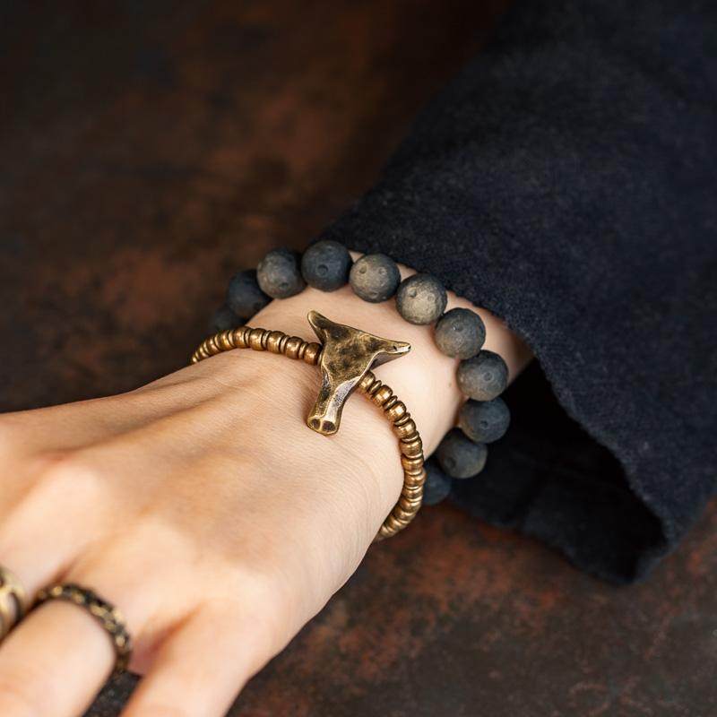 Rugged masculine bracelet stack featuring distressed gold-toned brass elements, a bull head pendant, and a spiral charm for a bohemian look.