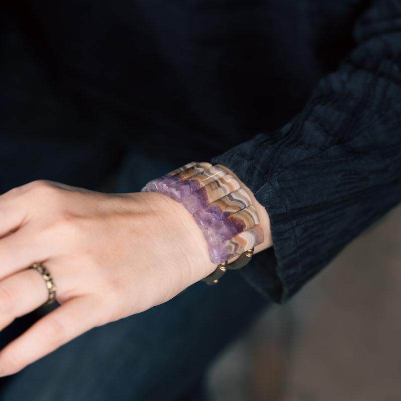 Side view of Serene Lucky amethyst slab bracelet, showing the rhythmic arrangement of chunky purple crystal slabs and elongated brass tubes.