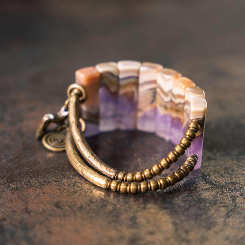 Serene Lucky brand banner showcasing a statement link bracelet made of rectangular amethyst slabs and antiqued brass bars with a spiral sun charm.