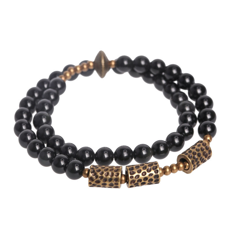 Main product view of Serene Lucky's Celestial Weaver bracelet with obsidian beads and hollow lattice brass spheres.