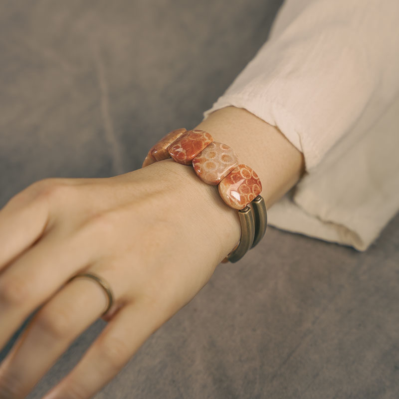 Lifestyle shot of a woman wearing the Serene Lucky Fossil Coral and Brass slab bracelet, demonstrating its bold yet organic modern aesthetic.