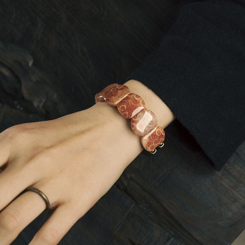 Lifestyle shot of a woman wearing the Serene Lucky Fossil Coral and Brass slab bracelet, demonstrating its bold yet organic modern aesthetic.