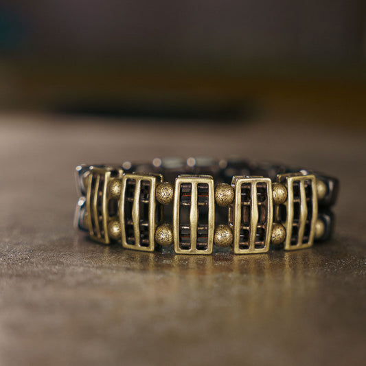Serene Lucky artisanal bracelet featuring rectangular Ebony wood slabs and textured antiqued brass focal beads on a minimalist background.