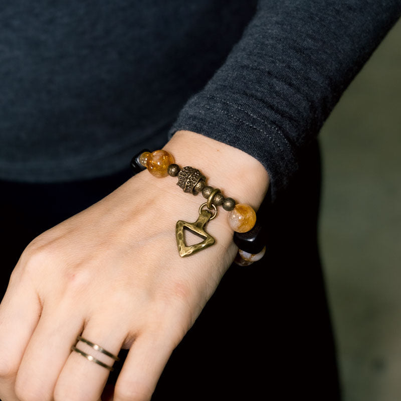 Macro detail of Serene Lucky Golden Clarity bracelet, showing intricate floral-etched brass cylinders and the natural inclusions within a radiant yellow citrine bead.