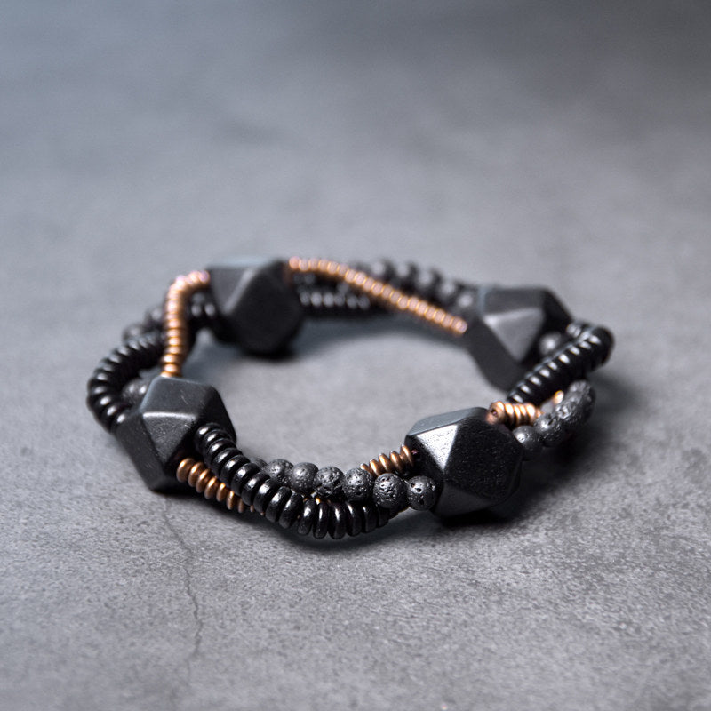 Serene Lucky handmade bracelet featuring porous Lava Stone, smooth Ebony Wood beads, and a geometric antiqued brass focal point.
