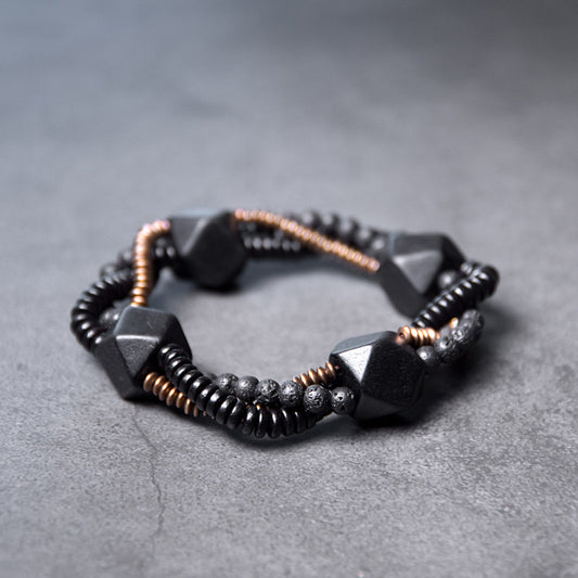 Serene Lucky handmade bracelet featuring porous Lava Stone, smooth Ebony Wood beads, and a geometric antiqued brass focal point.