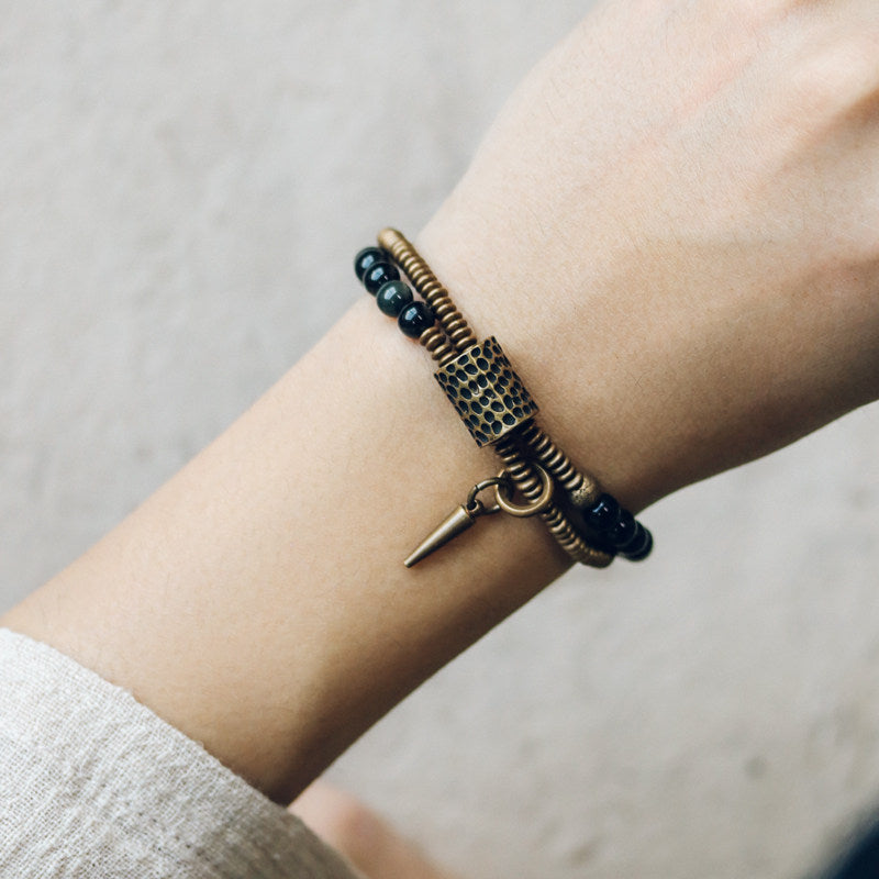 On-model shot of Serene Lucky's Midnight Fortress multi-wrap bracelet, featuring glossy black obsidian beads and architectural brass accents for a bold, unisex look.