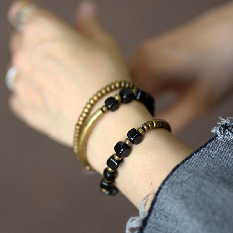Side view of Serene Lucky's Night Rhythm wrap bracelet on a model's wrist, showcasing the dynamic movement of the brass spikes and square obsidian beads.